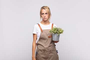 young woman gardener feeling sad, upset or angry and looking to the side with a negative attitude,...
