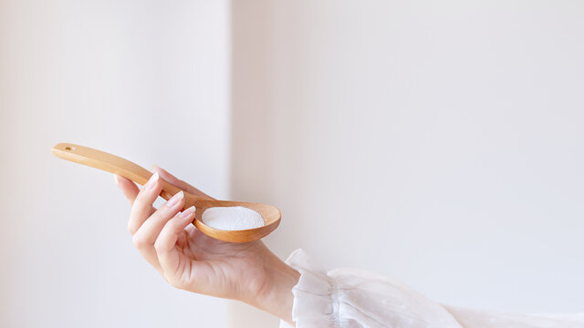 Woman in white blouse holding in hand wooden spoon with magnesium or calcium supplement powder. Bioactive additive woman pharmacy. Vitamin mineral treatment. Infant formula. Protein powder. Close up