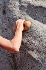 Closeup of arm and hand gripping a rock wall