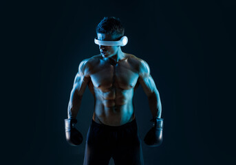Fototapeta na wymiar Muscular model sports young man in glasses of virtual reality and boxing gloves on dark background. Fashion portrait of strong brutal guy. Sexy torso. Male flexing his muscles. VR. Blue neon light.
