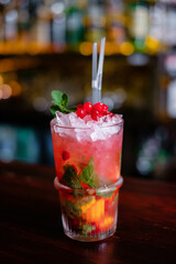 Making cocktails at home like an expert nightclub barman. Fresh and juicy colorful homemade cocktails garnished with berries, orange, mint.