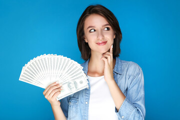 Young woman holding dollar banknotes on blue background