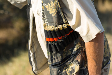 Duck hunter with shotgun walking through a meadow.