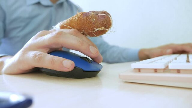 hand of a man with a bandaged finger uses a computer mouse and keyboard
