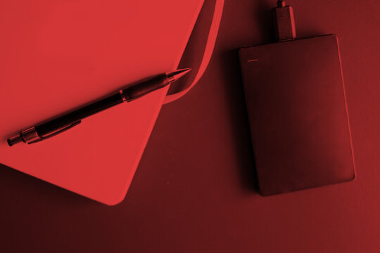 hard disck, notebook and pen. red tone home office background