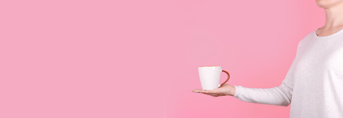 Fototapeta na wymiar Hand with white coffee cup. Isolated on pink background, copy space template, banner.