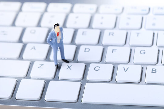 Miniature people on white computer keyboard