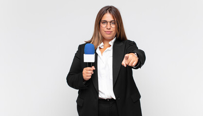 young woman reporter pointing at camera with a satisfied, confident, friendly smile, choosing you