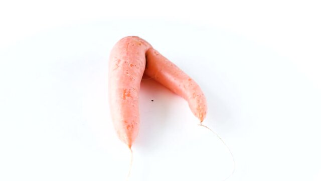 Ugly carrot rotate on a white background. Funny, unnormal vegetable or food waste concept. Horizontal orientation