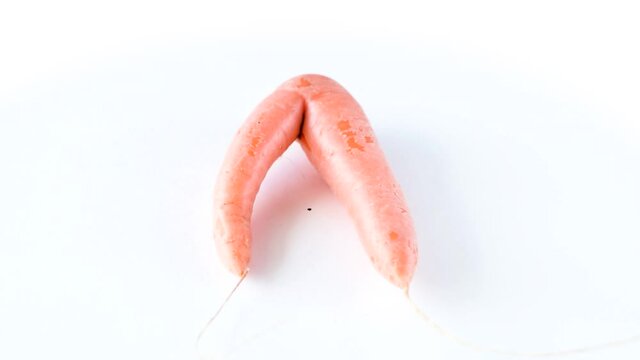 Ugly carrot rotate on a white background. Funny, unnormal vegetable or food waste concept. Horizontal orientation