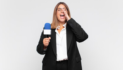 young woman reporter feeling happy, excited and positive, giving a big shout out with hands next to...