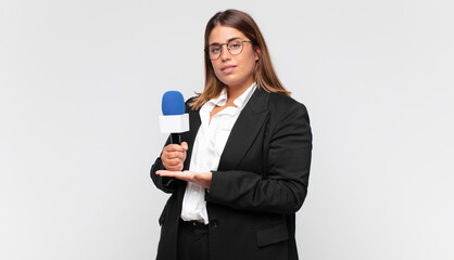 young woman reporter smiling cheerfully, feeling happy and showing a concept in copy space with...