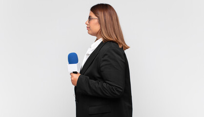 young woman reporter on profile view looking to copy space ahead, thinking, imagining or daydreaming