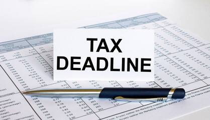 Text Tax Deadline on white card with blue metal pen on financial table