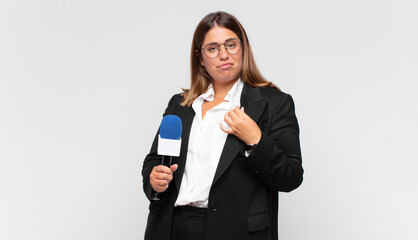young woman reporter looking arrogant, successful, positive and proud, pointing to self