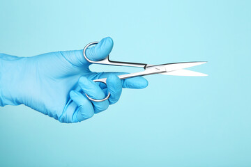 Doctor hand in glove holding scissors on blue background