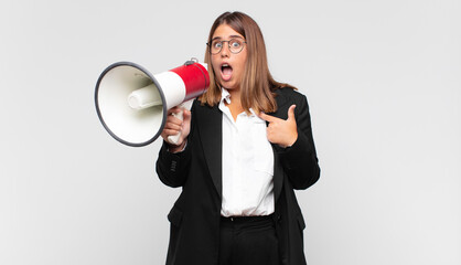 young woman with a megaphone looking shocked and surprised with mouth wide open, pointing to self