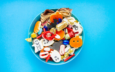 Halloween Jack o Lantern candy bowl with candy and halloween cookies Trick or Treat on blue background