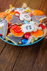 Halloween Jack o Lantern candy bowl with candy and halloween cookies Trick or Treat on black wooden background