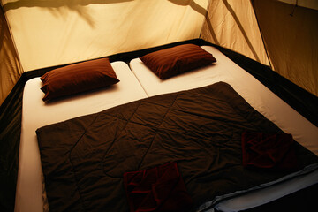 Comfortable beds inside elegant tent. Bed and pillows in luxurious camping tent.
