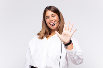 young woman telemarketer smiling and looking friendly, showing number five or fifth with hand...