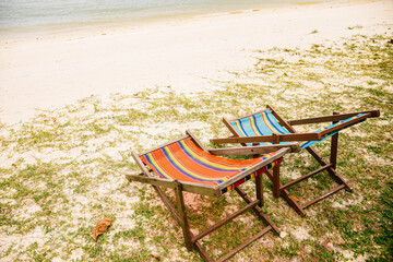 Fototapeta na wymiar Colorful colorful lounge chairs at tropical beach in Caribbean with beautiful turquoise ocean water. Concept of summer vacation and relaxation. 