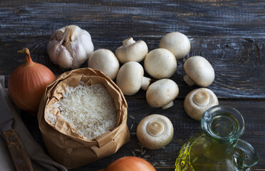 Ingredients for a delicious vegan dish. White basmati rice, garlic, onion and champignons mushrooms on a wooden table, top view, space, horizontal	