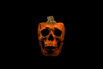 Front view of a spooky skull isolated on black background. Pumpkin with skull face. Symbol of the autumn holiday.