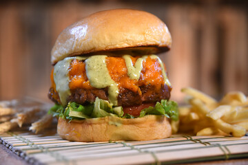 hamburger sandwich with open brioche bread cream cheese fries bacon sauces on the table on blurred background