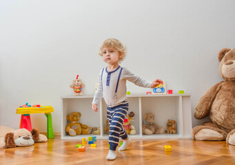 Cute little child having fun playing with colorful wooden blocks, at home