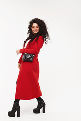 Full-length portrait of a young gorgeous woman in a red coat and boots on high heels, isolated at white.