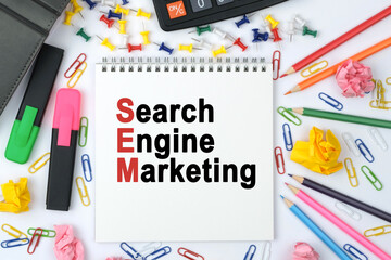 On the table is a calculator, diary, markers, pencils and a notebook with the inscription - Search Engine Marketing