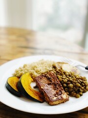simple plate of vegetarian / vegan food with tofu, lentils and pumpkin, vertical photo with copy space
