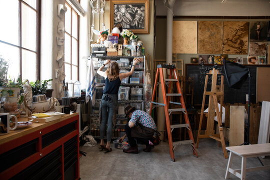 Artists organizing equipment on shelves in art studio