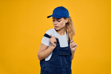 Woman in working uniform blue cap delivering courier service yellow background