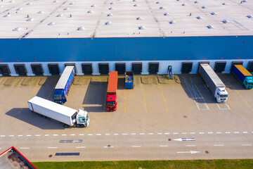 Aerial view of goods warehouse. Logistics center in industrial city zone from above. Aerial view of trucks loading at logistic center