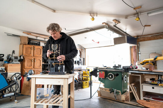 Male sculptor assembling wine glass sculpture in workshop garage