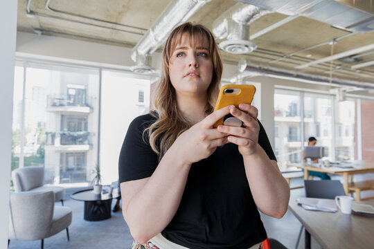 Businesswoman using phone in bright coworking space