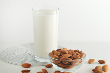 A glass with almond milk and the bowl with almonds