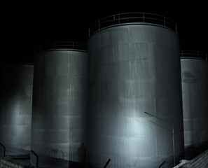 .Metallic storage tanks at night in an industrial facility