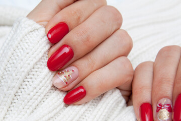 Creative New Year's manicure red with a pattern of a Christmas tree on a sweater background