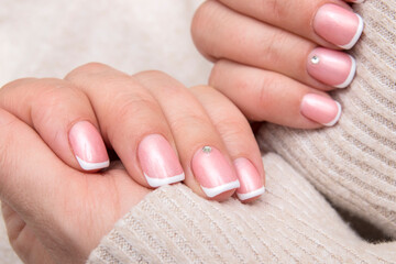 Women's hands with French manicure and rhinestones on rectangular nails on the background of a...