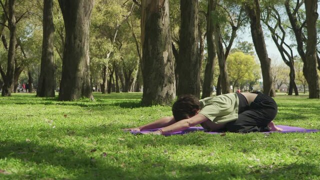 Parallax shot of a woman doing the Child's pose of yoga at park. High quality 4k footage with copy space