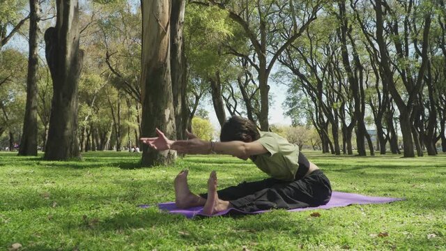 A pretty short haired woman doing the seated forward bend pose of yoga. High quality 4k footage