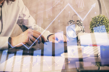 Double exposure of man's hands holding and using a phone and financial graph drawing. Analysis concept.