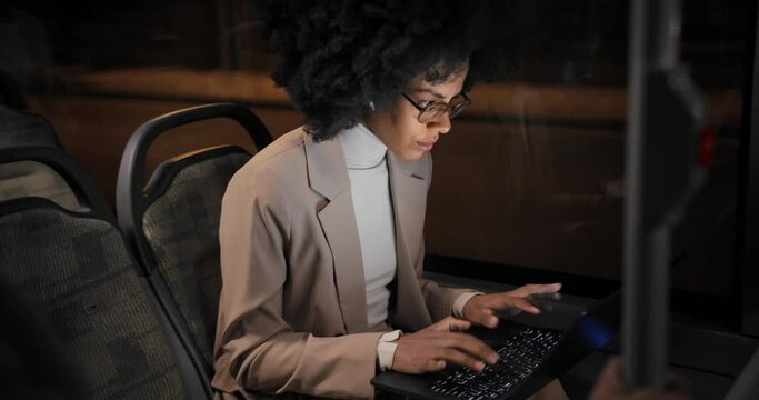 African-american Business Woman Working On Laptop Wearing Earphones On Bus