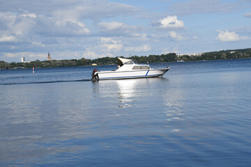 Obraz premium Ein Boot fährt auf dem Tollensesee vor den Toren Neubrandenburgs. Der See und die Stadt liegt im Gebiet der Mecklenburgischen-Seenplatte in Mecklenburg-Vorpommern. Viele Radwege 