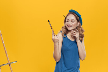 Artist woman in blue beret brush easel art drawing education hobby Creative approach yellow background