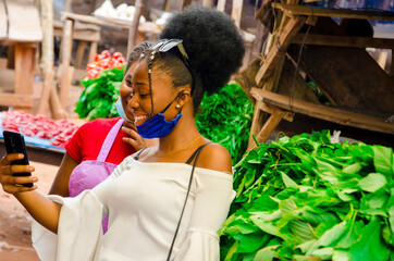 young beautiful african trader and her customer wearing face mask feeling excited about on their...