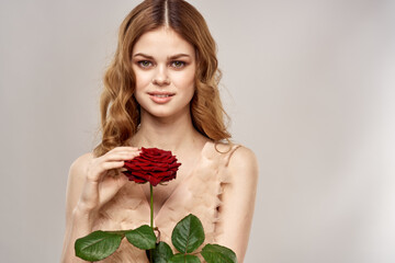 Portrait of a beautiful woman with a red rose on a beige background cropped view of an evening dress